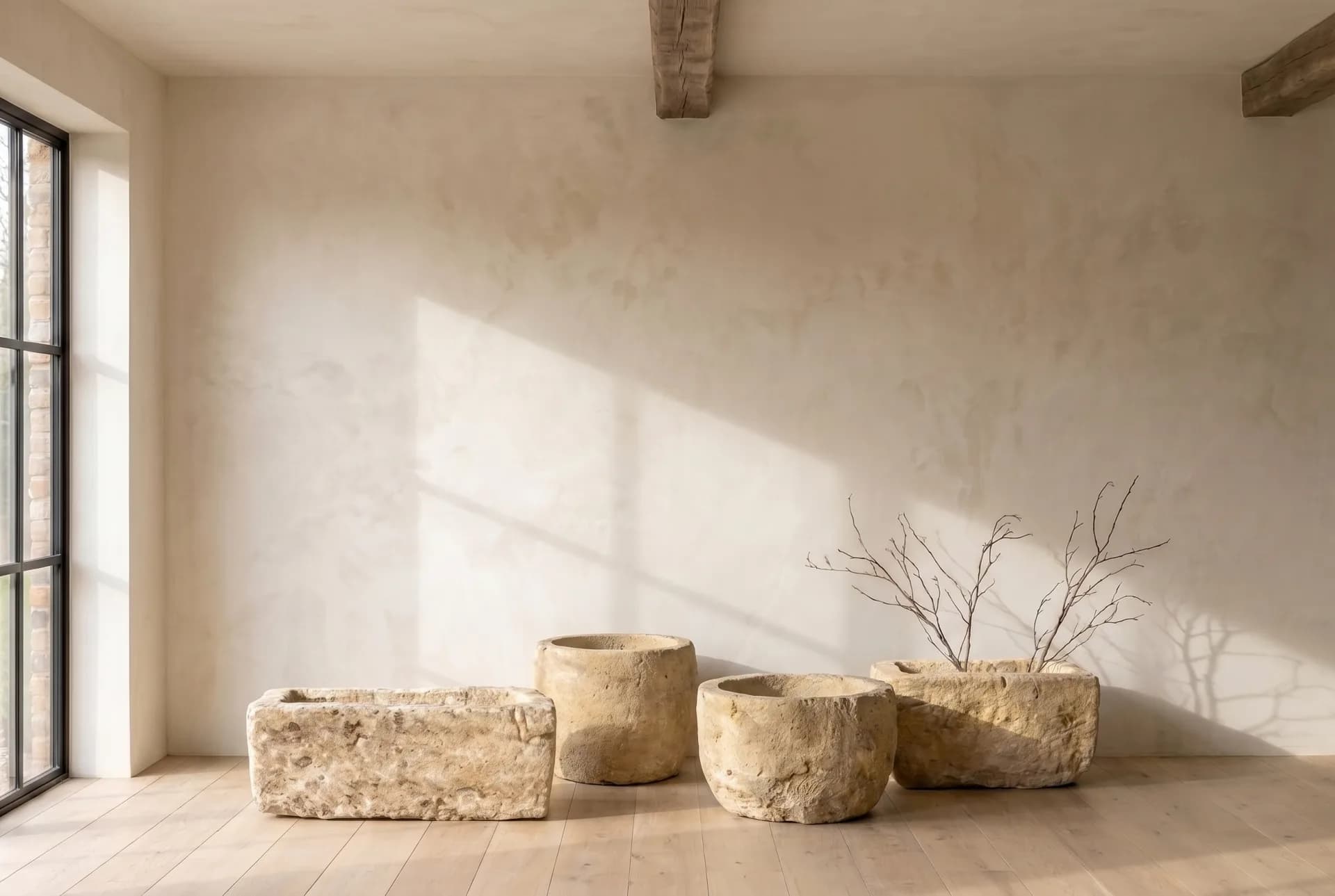 Natuurstenen potten en troggen samen in een lichte plaster-ruimte bij het raam
